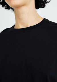 Zwarte katoenen t-shirt, met ronde hals, met een gladde textuur en subtiele schouderdetails. Minimalistische en veelzijdige stijl.