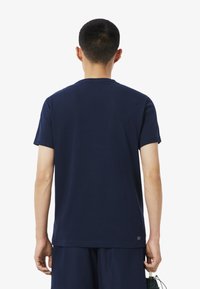 Camiseta de algodón azul marino de manga corta y cuello redondo. Presenta un logo sutil en el dobladillo y una textura suave.