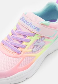Skechers tenisky s textilním svrškem, který má gradient růžové, žluté a mátové zelené. S suchým zipem a fialovými akcenty. Bílé podešve.