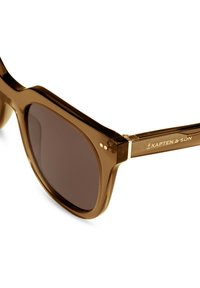 Occhiali da sole in plastica marrone con montatura quadrata, lenti scure e dettagli dorati sulle tempie, con il marchio "Kapten & Son."