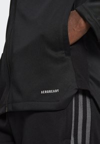 Black athletic jacket with a smooth texture, featuring a zippered closure and an "AEROREADY" logo on the front. Vertical striped accents visible.