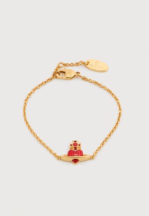 Złota bransoletka z czerwonym zawieszką w kształcie korony o gładkiej fakturze i wyraźnym kamieniu szlachetnym. Regulowany łańcuszek z zapięciem na zatrzask.