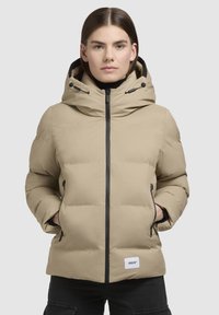 Beige Steppjacke mit hohem Kragen, schwarzen Reißverschlüssen und verstellbare Kapuze. Verfügt über Seitentaschen und einen Logo-Patch auf der unteren Vorderseite.