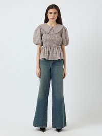 Checkered puff-sleeve blouse with a large collar, fitted bodice, and peplum hem, paired with high-waisted wide-leg denim jeans.