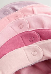 Penki audinio spaudžiami užsegimai, įvairių rožinės ir levandų atspalvių, su minkštu tekstilės audiniu, lygiu paviršiumi ir apvalia forma.