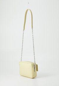Yellow rectangular crossbody bag with a smooth finish, featuring a detachable chain strap, zip closure, and a side pocket accent.