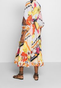 Robe colorée et à motifs, présentant des motifs floraux et des rayures. Fabriquée en tissu léger, avec une silhouette fluide et de longues manches bouffantes.