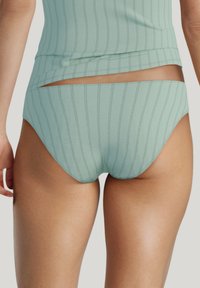 Mintgroene short met verticale ribbelstructuur, voorzien van een uitsnede in de tailleband, gemaakt van zachte, rekbare stof voor comfort.