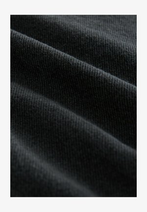 Tumehall hall, millel on peen, pehme tekstuur ja nähtavad kudumismustrid, luues sileda välimuse õrnade voldidega.