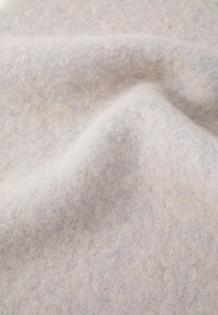Tessuto in feltro grigio chiaro con una superficie morbida e texturizzata, caratterizzato da sottili variazioni di colore e un aspetto leggermente peloso.