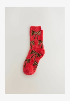 Piros bolyhos zokni leopárdmintás masnival. Puha textúrájú, bordás szegéllyel. Ideális melegségért és kényelemért.