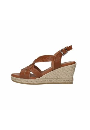 Brown leather wedge sandal with a braided front strap and adjustable ankle buckle. Tapered woven jute sole adds texture and height.