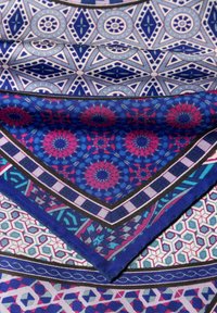 Silk scarf featuring intricate geometric patterns in shades of blue, pink, and white. Edges bordered with solid navy trim.