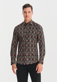 Czarna koszula zapinana na guziki z długim rękawem, z kwiatowym i geometrycznym wzorem w odcieniach różu, zieleni i żółci na ciemnym tle.