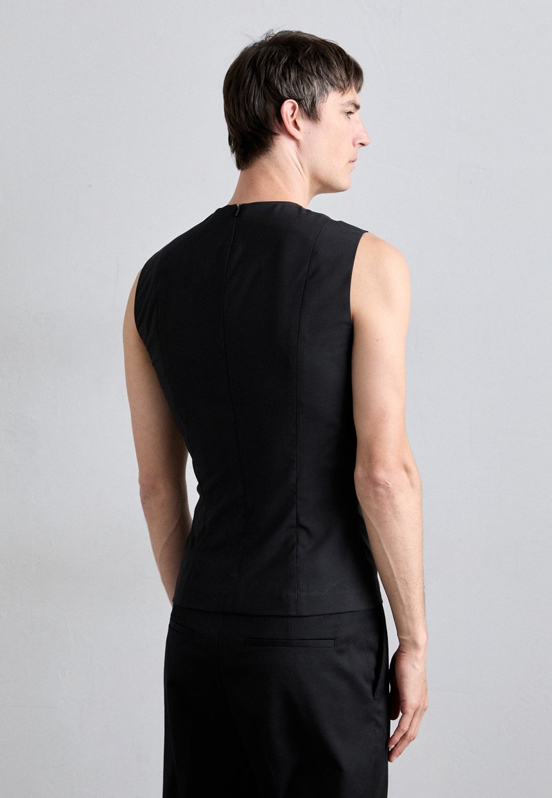 Black sleeveless top with a fitted design, featuring a round neckline and a discreet back zipper. Smooth texture, minimal detailing.