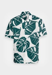 Camicia a maniche corte con sfondo bianco e grandi motivi di foglie di monstera verde scuro. Presenta una chiusura con bottoni e un colletto classico.