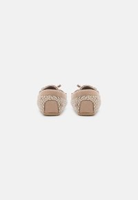 Beige schoenen met een geweven textuur en zachte suède bovenkant. Ronde vorm met een kleine hak en contrasterende details aan de achterkant.