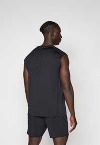 Čierne bezrukávové športové tričko s jemne potlačeným nápisom "BORG" na chrbte, v kombinácii s čiernymi šortkami. Hladký materiál, voľný strih.