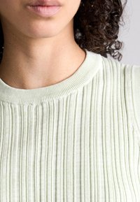 Světle zelený pletený svetr s kulatým výstřihem, s vertikálními pruhy a měkkým, strukturovaným materiálem.