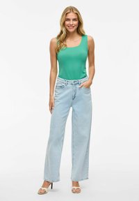 Zelena brezrokavnik kombinirana z visokim pasom svetlo modrimi širokimi hlačami. Obleka je dopolnjena z bež petami. Preprost dizajn, sproščen videz.