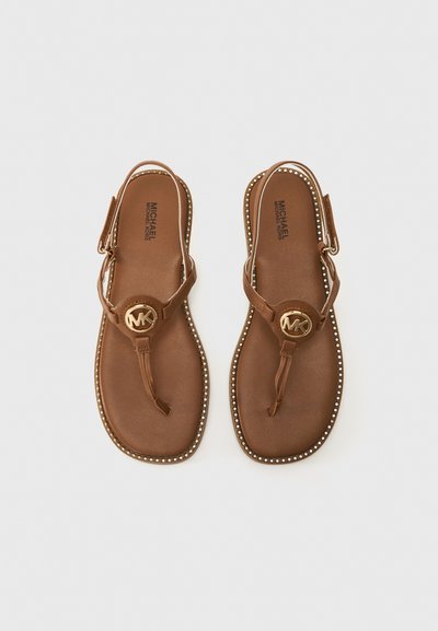 Bruna sandaler med en rem och spänne som har en cirkulär logotyp. Sulan är slät med små nitar längs kanten.
