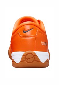 Des chaussures Nike orange présentent un dessus en synthétique lisse, un col rembourré et une semelle extérieure blanche contrastante avec un détail de logo circulaire.