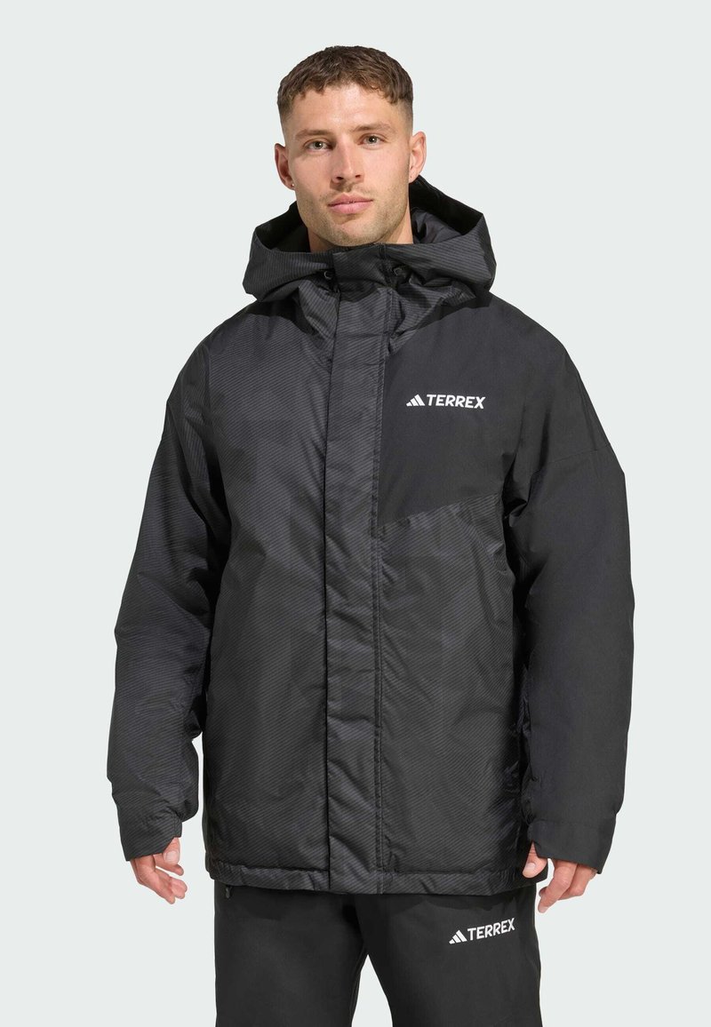Schwarze isolierte Jacke mit strukturierter Oberfläche, ausgestattet mit einer Kapuze, Reißverschluss und einem kontrastierenden weißen Logo auf der Brust und dem Ärmel.