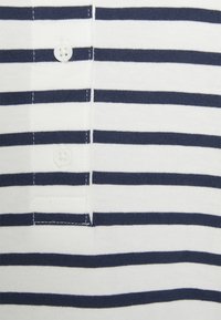 Polo rayé bleu marine et blanc avec une patte de boutonnage à trois boutons et une texture douce en coton. Les rayures sont espacées de manière uniforme.