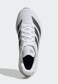 Weißer Sportschuh mit einem strukturierten Mesh-Obermaterial. Verfügt über schwarze Streifen und Akzente. Leichtes Design mit einer abgerundeten Zehenpartie und gepolstertem Kragen.