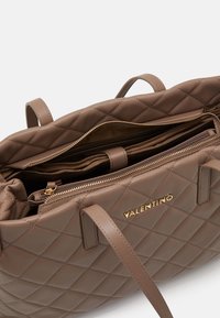 Kvadrovaná hnědá kožená kabelka s zlatými kovovými doplňky. Obsahuje prostorný vnitřek, zipové kapsy a dvojité ucho pro pohodlné nošení.