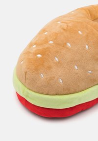 Slap za cipele u obliku hamburgera s bež gornjim dijelom, zelenim dodatkom zelene salate i crvenim donjim dijelom peciva. Mekana tekstura s izvezenim sjemenkama sezama.
