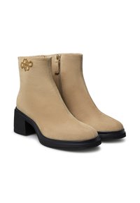 Stivaletti alla caviglia in suede beige con un design elegante, chiusura con zip e tacco a blocco nero, impreziositi da un dettaglio con logo dorato.