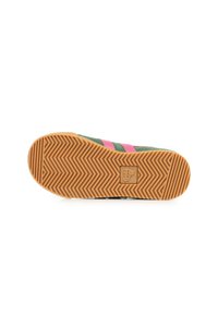 Sneaker verde in tela con strisce rosa sui lati, una suola in gomma testurizzata con motivo a spina di pesce e un logo sul tallone.