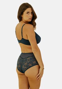 Bralette en dentelle bleue et culotte taille haute, avec des motifs floraux et une texture de tissu lisse. Bretelles réglables et bordure en dentelle détaillée.