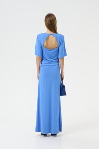 Blue maxi dress with short sleeves, draped detailing, and an open back. Smooth fabric; paired with a small blue bag. Tailored fit.