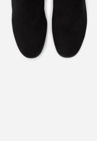 Botas de tobillo de ante negro con una textura suave y puntera redondeada. Diseño elegante sin herrajes o acentos visibles.