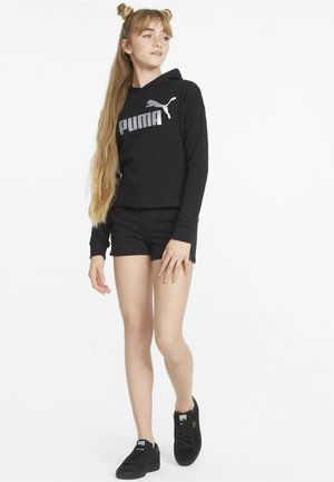 Felpa nera con logo argento "PUMA", pantaloni corti neri abbinati e sneakers nere. Il tessuto appare liscio con un design a vestibilità rilassata.