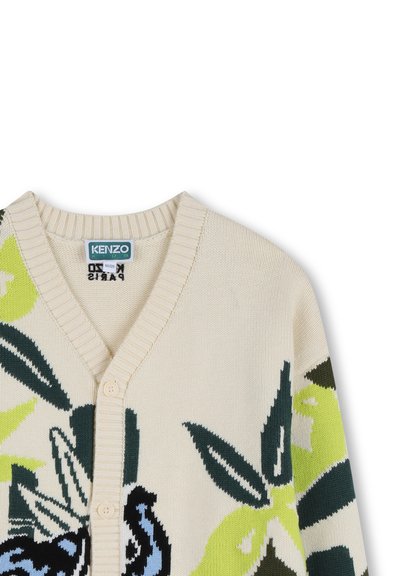Cardigan beige en tricot avec un motif floral en vert, bleu et noir. Encolure en V avec bords côtelés et fermeture à deux boutons.
