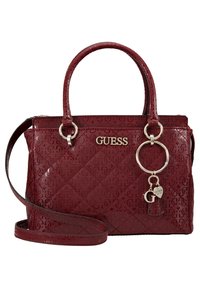 Sac à main synthétique rouge avec texture matelassée, logo embossé, double poignée, bandoulière amovible et breloques décoratives.