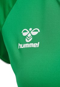 Grøn sportstrøje lavet af glat stof, med et hvidt logo og brandnavnet "hummel" på brystet. Korte ærmer, tætsiddende design.