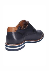 Scarpa da donna in pelle blu navy con tacco marrone testurizzato, area della punta traforata e suola a righe blu-bianca, mostrata dal retro.