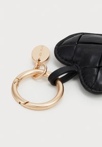 Fekete bőr, szív alakú kulcstartó, steppelt mintázattal, arany színű fém kulcskarikához és címkéhez rögzítve.