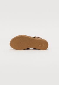Sandal in pelle marrone con suola in gomma testurizzata, cinturino regolabile con fibbia e design aperto sulla punta per traspirabilità e comfort.