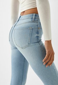 Ljusblå denim skinny jeans med fem fickor, sömdekor och hög midja. Tyget har en mjuk textur och lätt stretch.