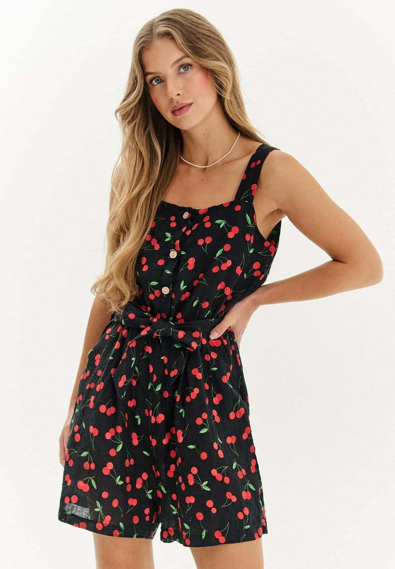 Černý bezrukávový overal s potiskem třešní, s knoflíkovou přední částí a opaskem v pase pro zvýrazněný tvar. Texturovaná látka s hravým designem.