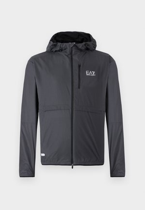 Ľahká čierna bunda s kapucňou, ktorá má zipsovú kapsu a detail loga na ľavej hornej strane. Vyrobená z hladkej, vodeodolnej tkaniny.