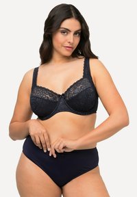 Soutien-gorge en dentelle bleu foncé avec armatures et motif floral, doté de larges bretelles et d'un accent en nœud au centre, associé à un slip taille haute bleu foncé.