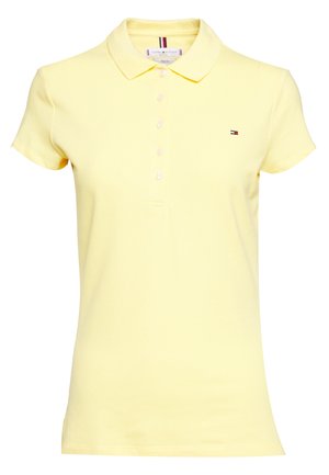 Polo en jaune pastel, à manches courtes, avec un col, une patte de boutonnage à cinq boutons et un petit logo sur la poitrine gauche. Tissu en coton doux.