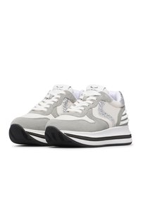 Baskets grises et blanches en matériaux de daim et de cuir, avec un accent en argent brillant, une semelle intermédiaire épaisse blanche et une semelle extérieure noire texturée.