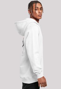 White hoodie with a kangaroo pocket, featuring a black graphic design on the front and an adjustable drawstring for the hood.